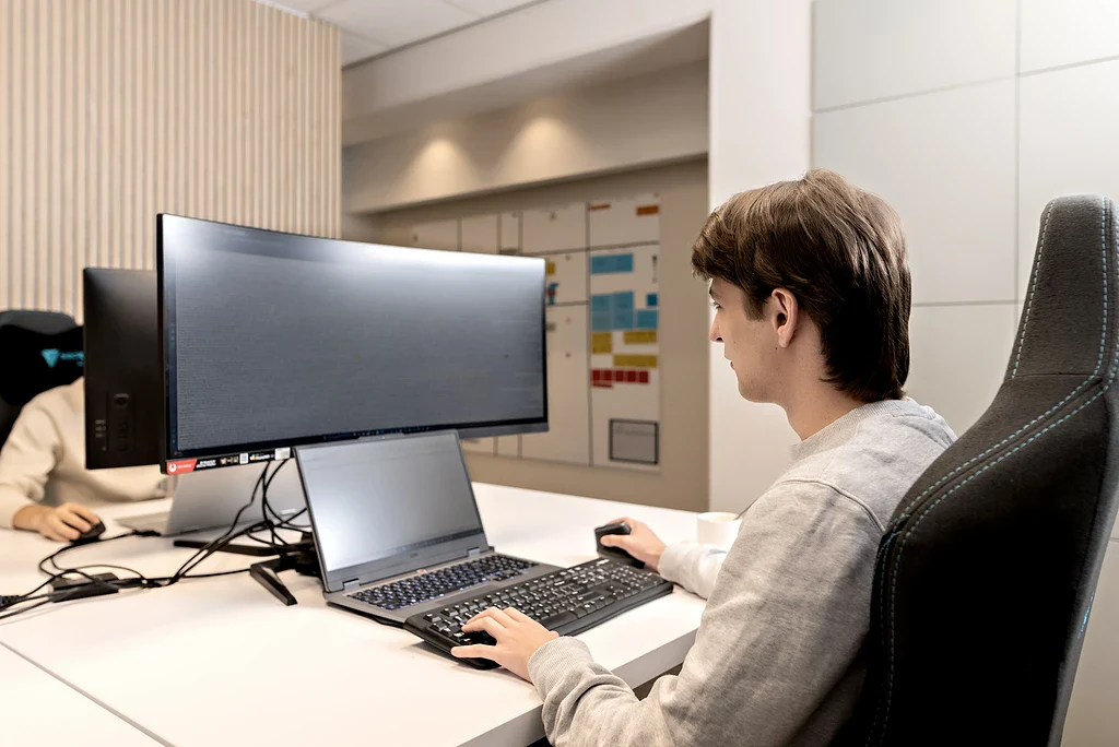 Twee collega's werken lachend samen aan een bureau